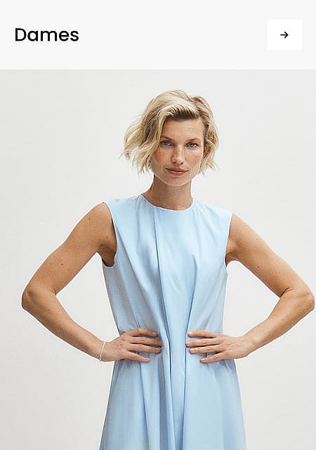 Vrouw met kort blond haar in een lichtblauwe mouwloze jurk, met de handen op de heupen, tegen een witte achtergrond. Koptekst: „Vrouwen”.