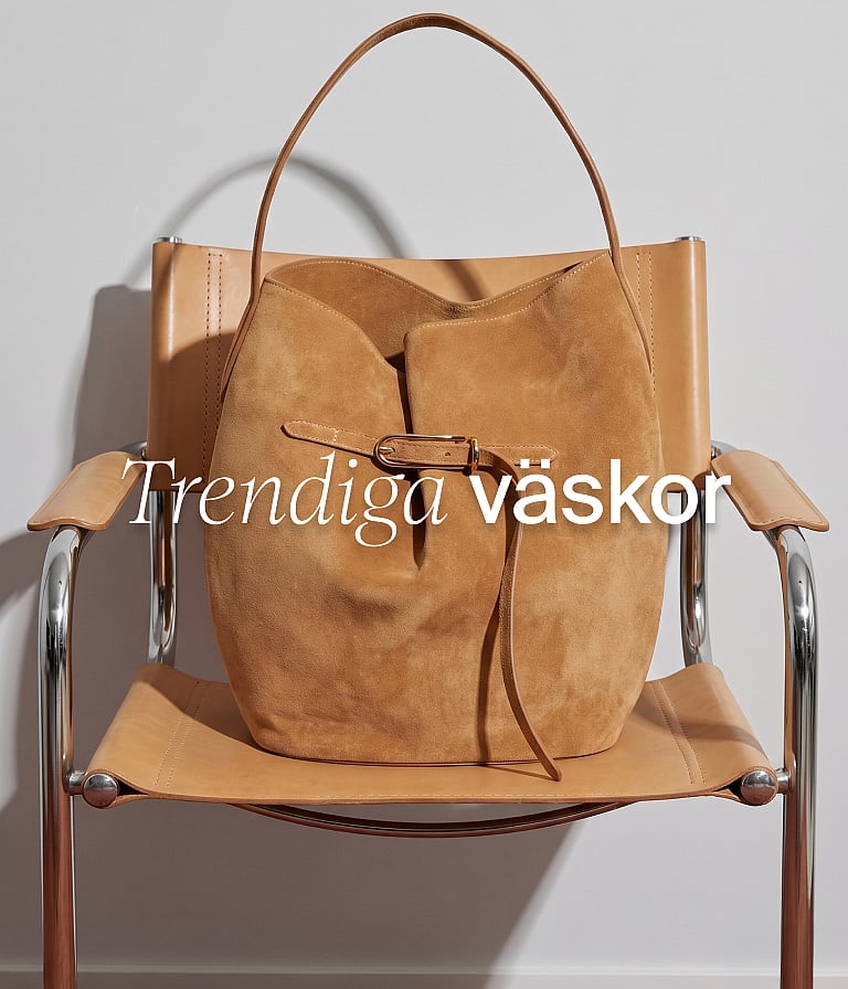 En beige mockahinkväska på en ljusbrun stol i läder och krom mot en vit vägg. Textöverlagring: ”Trendiga väskor”.