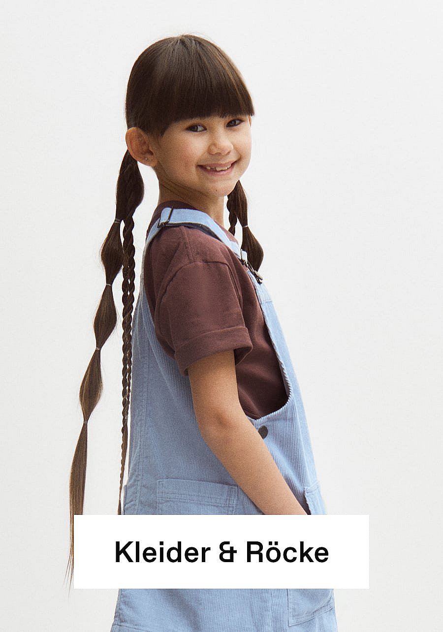 Lächelndes Mädchen mit langen Bubble-Zöpfen und Pony, das ein braunes T-Shirt und eine hellblaue Cord-Latzhose trägt. Text: Kleider und Röcke
