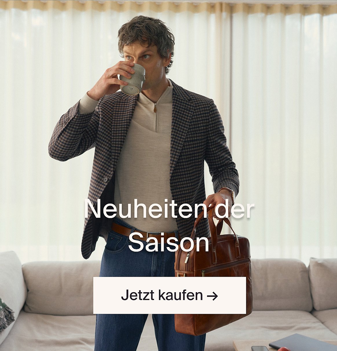 Modell in weisser Kurzarm-Bluse mit Lochstickerei und blauer Jeans, Hände in den Taschen, vor einer hellen Holzwand.