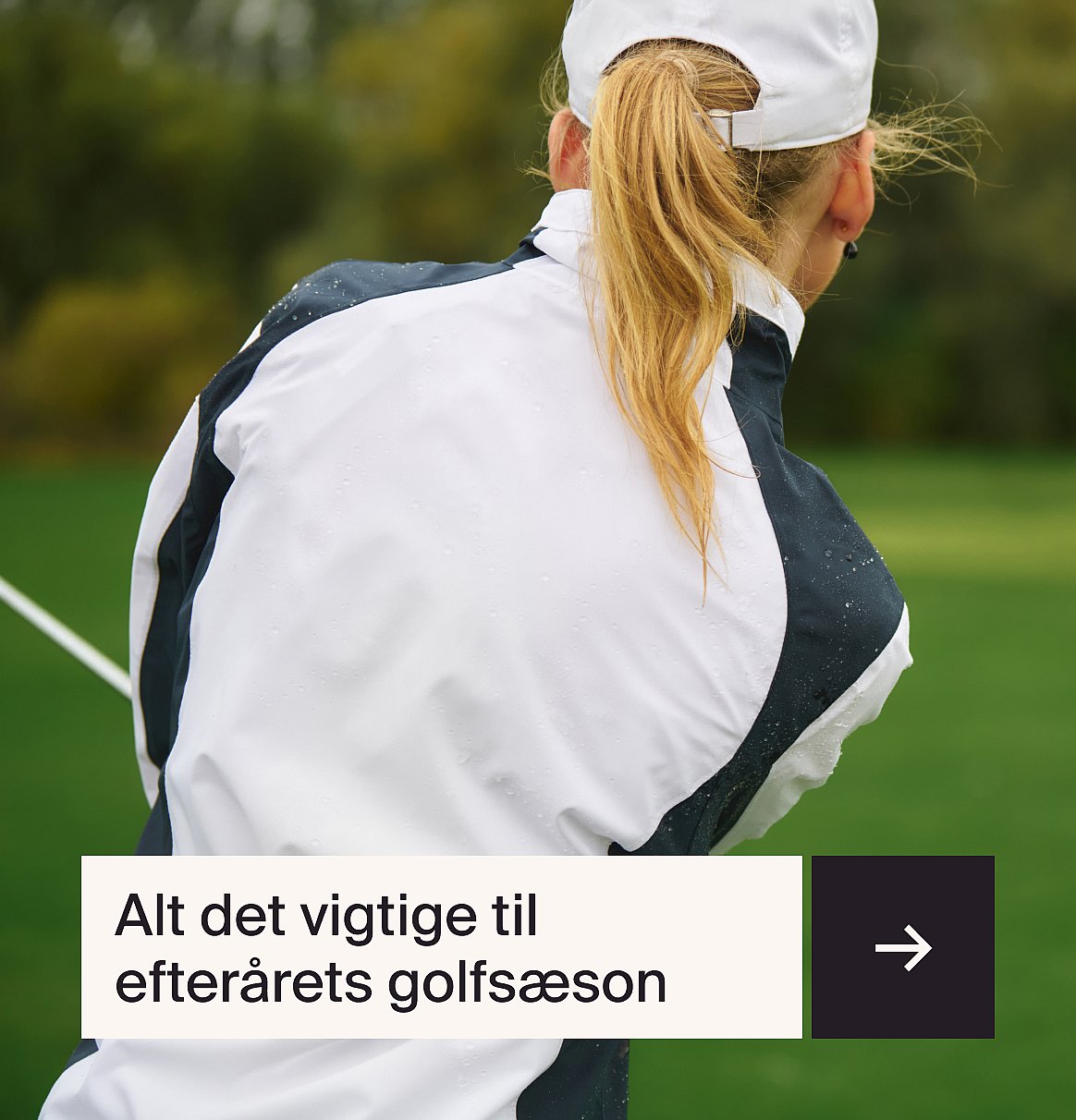 En kvindelig golfspiller set bagfra, med blond hestehale, iført en våd hvid og mørk jakke på en grøn golfbane. Tekst: Uundværlige golfartikler til efteråret.