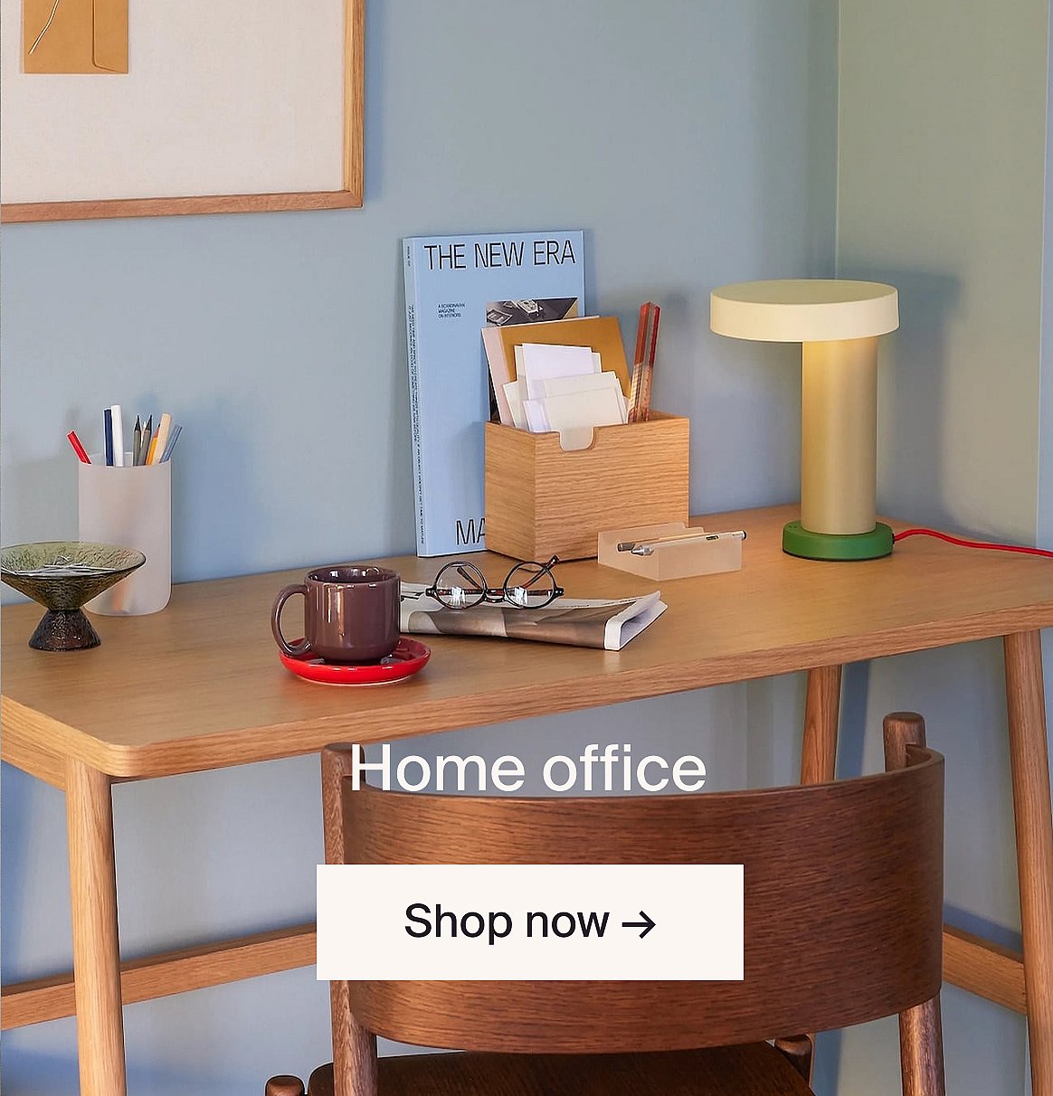 Light wood home office desk with a lamp, mug, glasses, and supplies against a blue wall. Text: Home office, Shop now.
