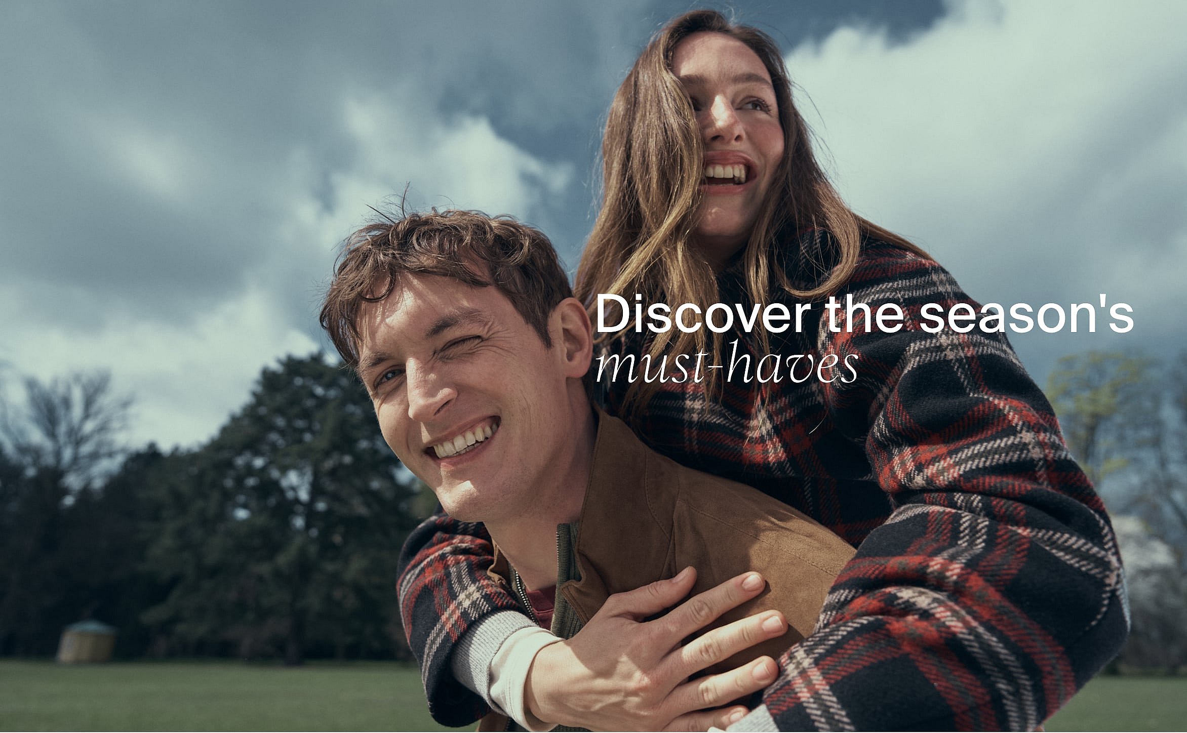 Smiling woman in sunglasses and colorful top next to man in pink polo, outdoors in sun. Text: Discover the season's