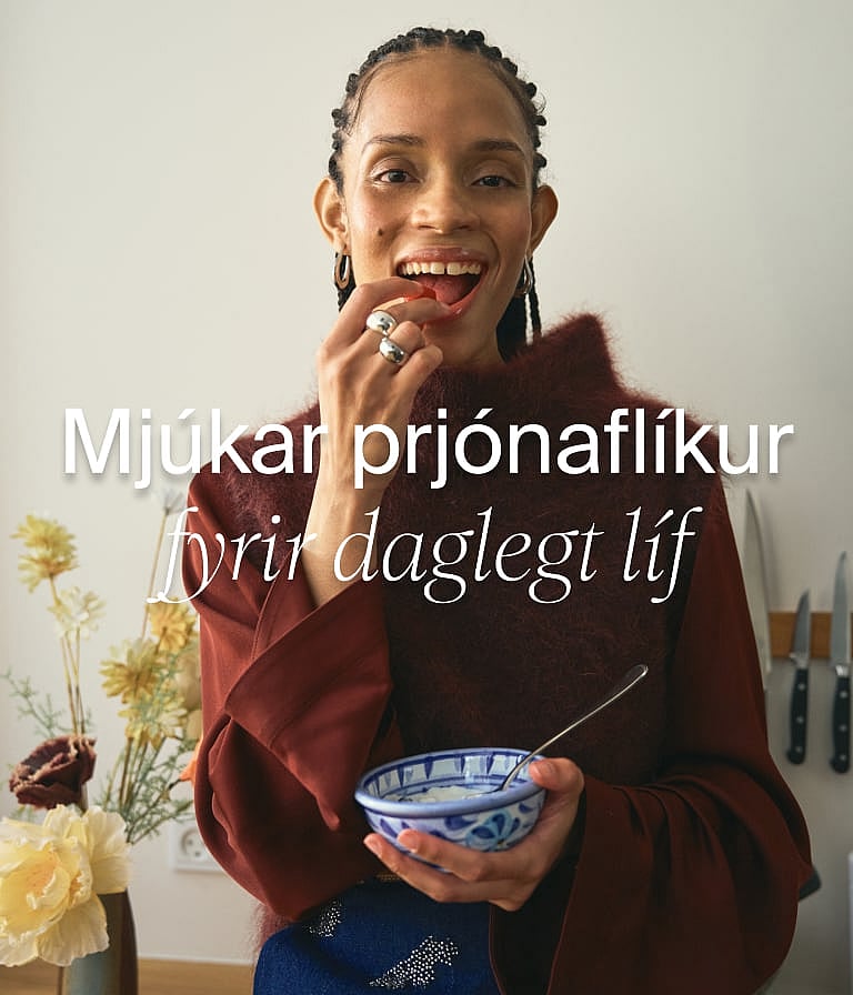 Kona í léttum hörklæðnaði að snæða máltíð við borð með mynstraðan dúk, við glugga með trjám. Texti: "Sumarskrifstofa"