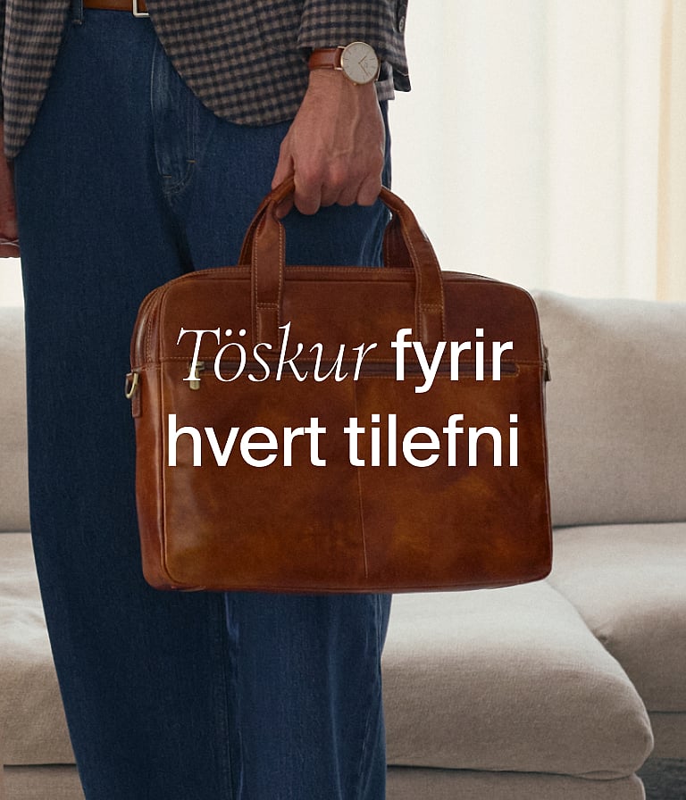Manneskja á sandströnd með röndóttum strandstól og bláum kæli. Klettar í bakgrunni.