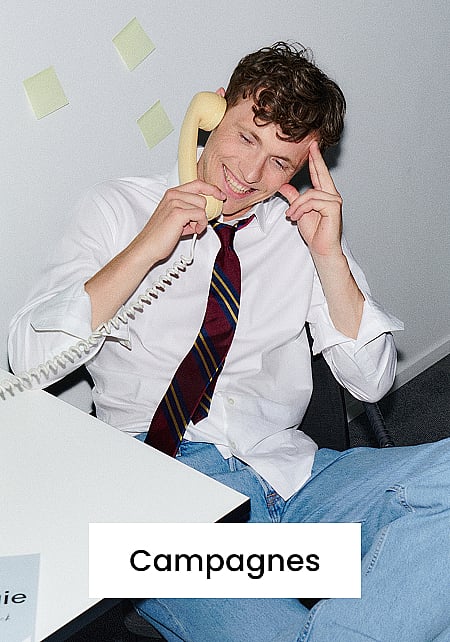 Een glimlachende man in een wit overhemd en een gestreepte stropdas praat via een gele retro-telefoon aan een bureau. Tekst: „Campagnes”.