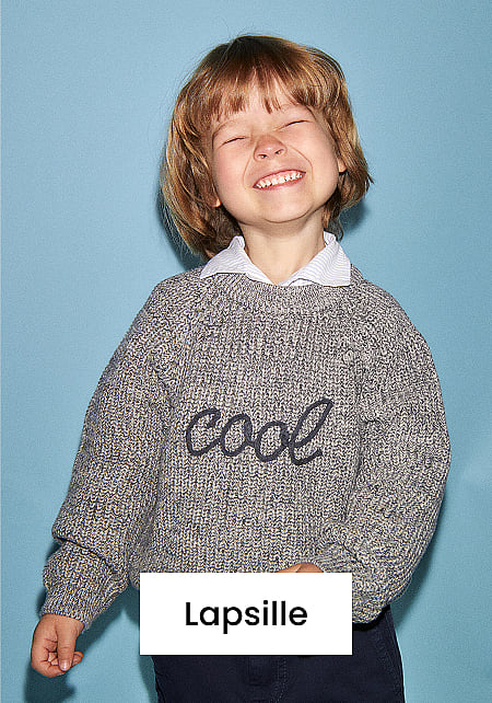 Onnellinen lapsi, silmät kiinni, yllään harmaa ”cool” villapaita ja tummat housut, sinisellä taustalla. Kuvassa teksti ”Kids”.