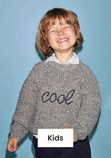 Happy child with closed eyes, wearing a grey "cool" sweater and dark pants, against a blue background. "Kids" text overlay.