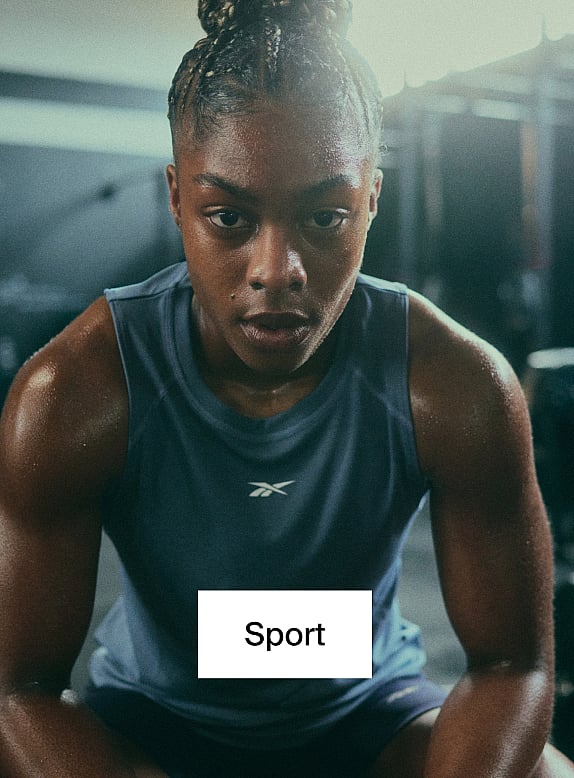 Eine verschwitzte Frau mit geflochtenen Haaren in einem blauen Trägertop, die in einem Fitnessstudio konzentriert nach vorne blickt. Aufschrift: Sport.