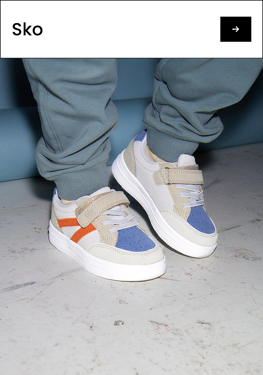 Et barns fødder i lysegrå, blå og orange sneakers på et lysegråt gulv. Tekst: Sko