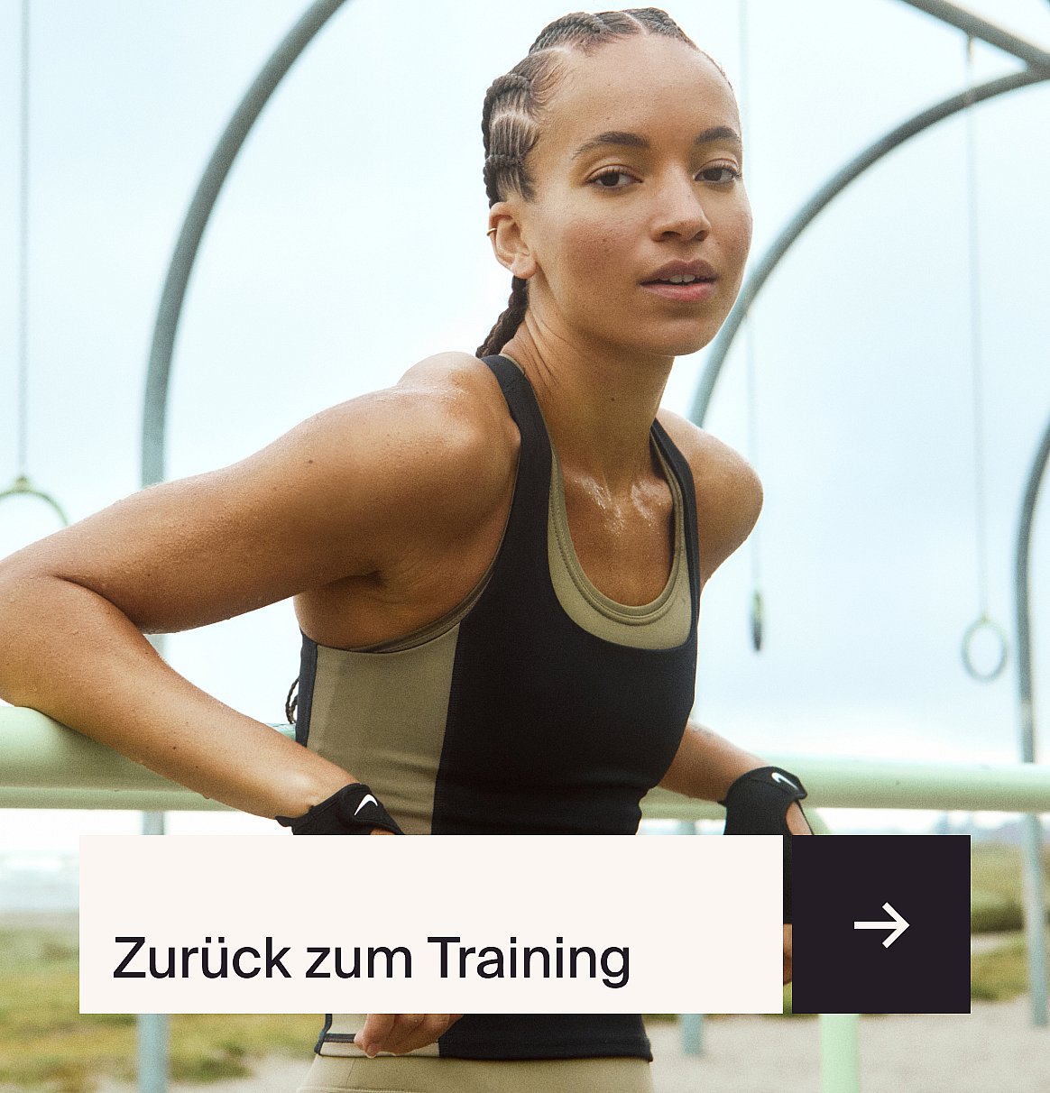 Eine Frau in einer reflektierenden Jacke und einer verspiegelten Sportsonnenbrille, die ihren Arm streckt, vor einer leuchtend gelben Wand.