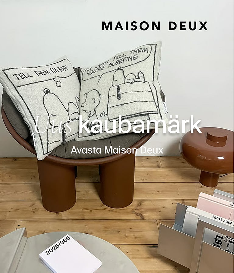 Kaks Snoopy-teemalist koomiksipatja kaasaegsel pruunil toolil. Tekst: MAISON DEUX, uus bränd.