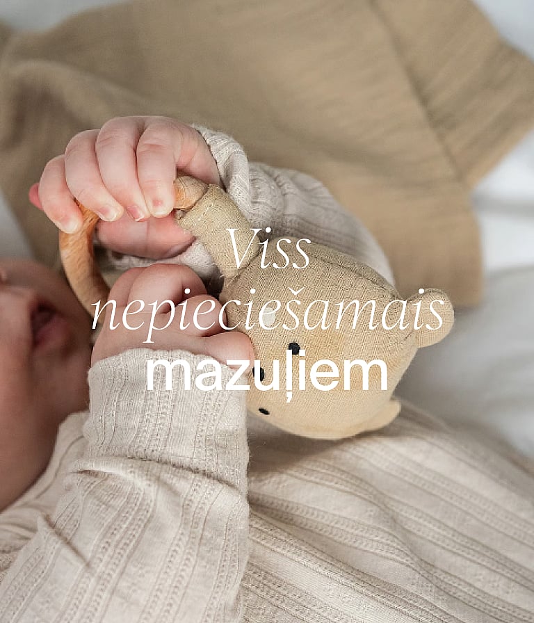 Mazuļa rociņas neitrālā apģērbā, turot auduma lācīti. Teksts attēlā: „Mazuļa pamatlietas“.