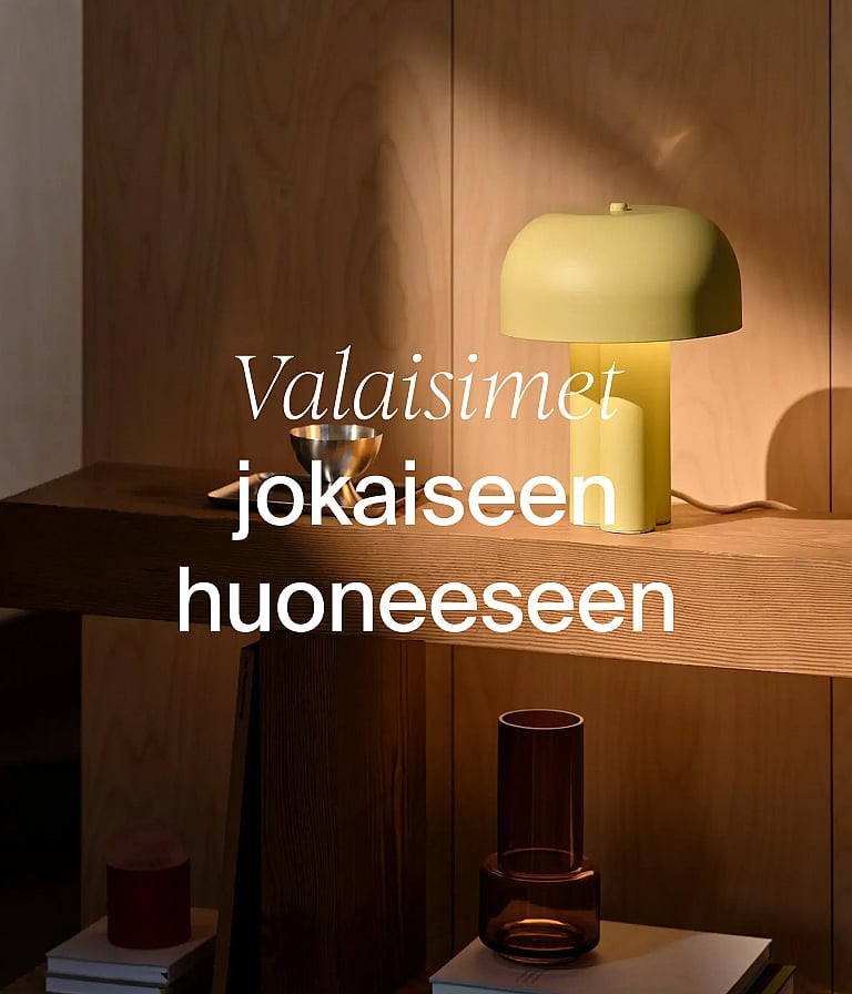 Vaaleankeltainen sienimainen lamppu puisen konsolipöydän päällä puisen seinän edessä. Teksti: ”Lamput joka huoneeseen.”