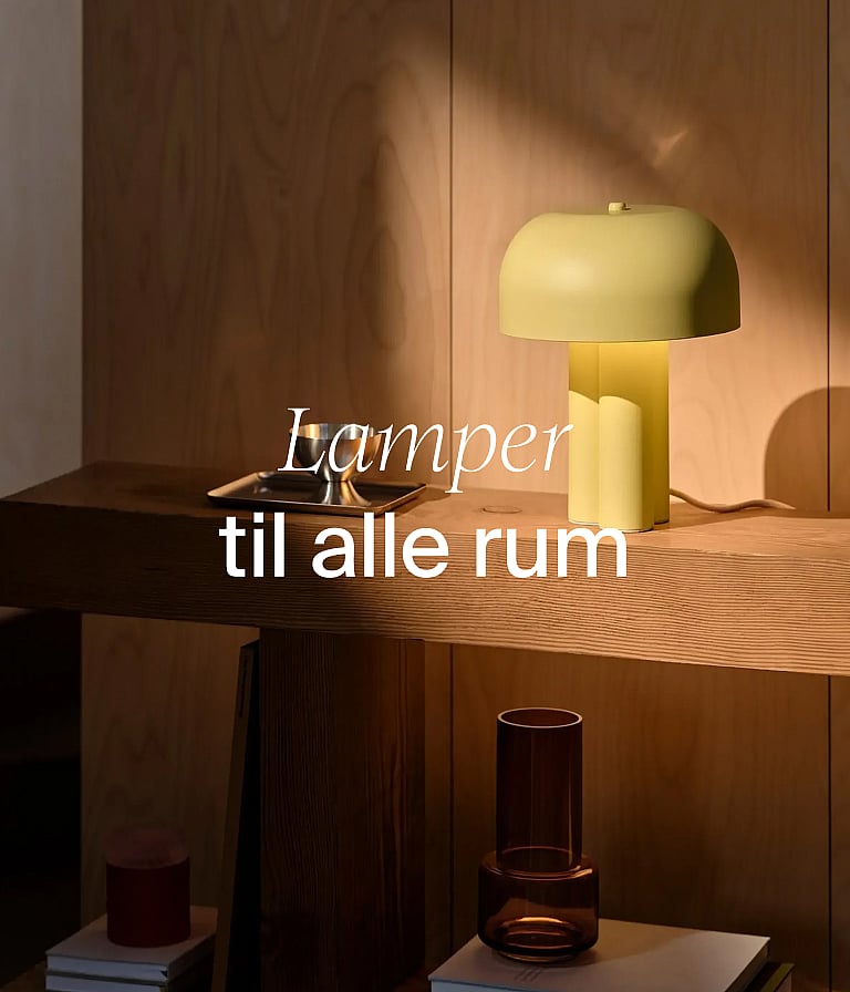 En lysegul svampelampe på et konsolbord af træ foran en trævæg. Tekst: »Lamper til alle rum.«