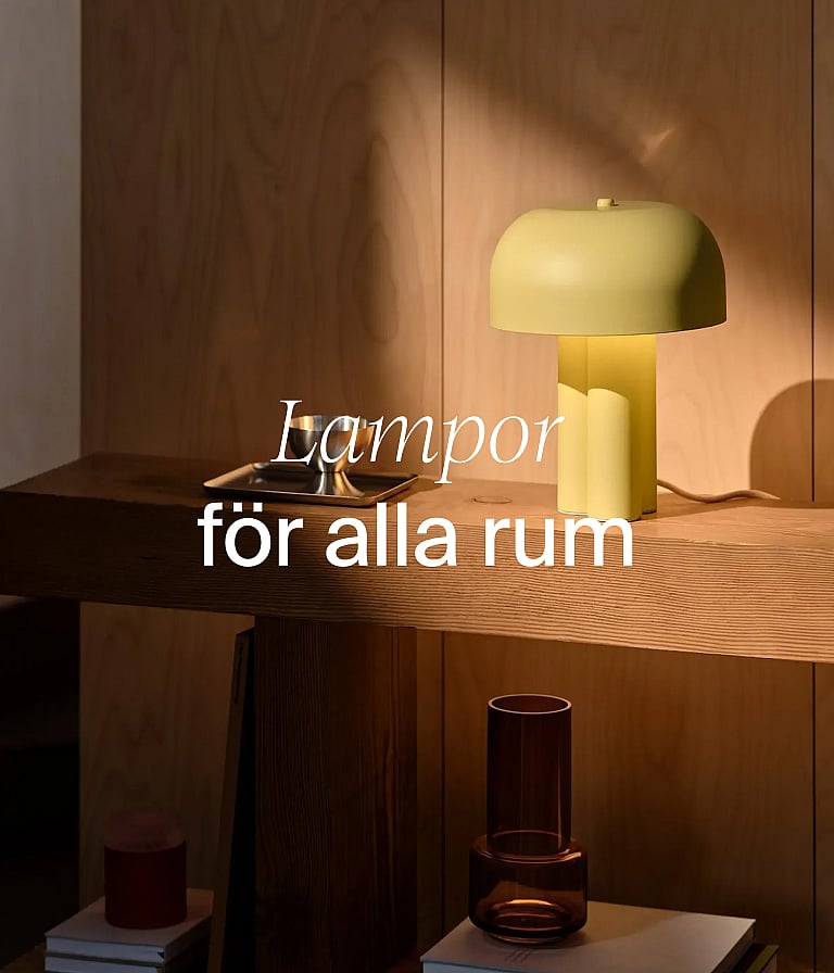 En ljusgul svamplampa på ett konsolbord i trä framför en trävägg. Text: ”Lampor för alla rum.”