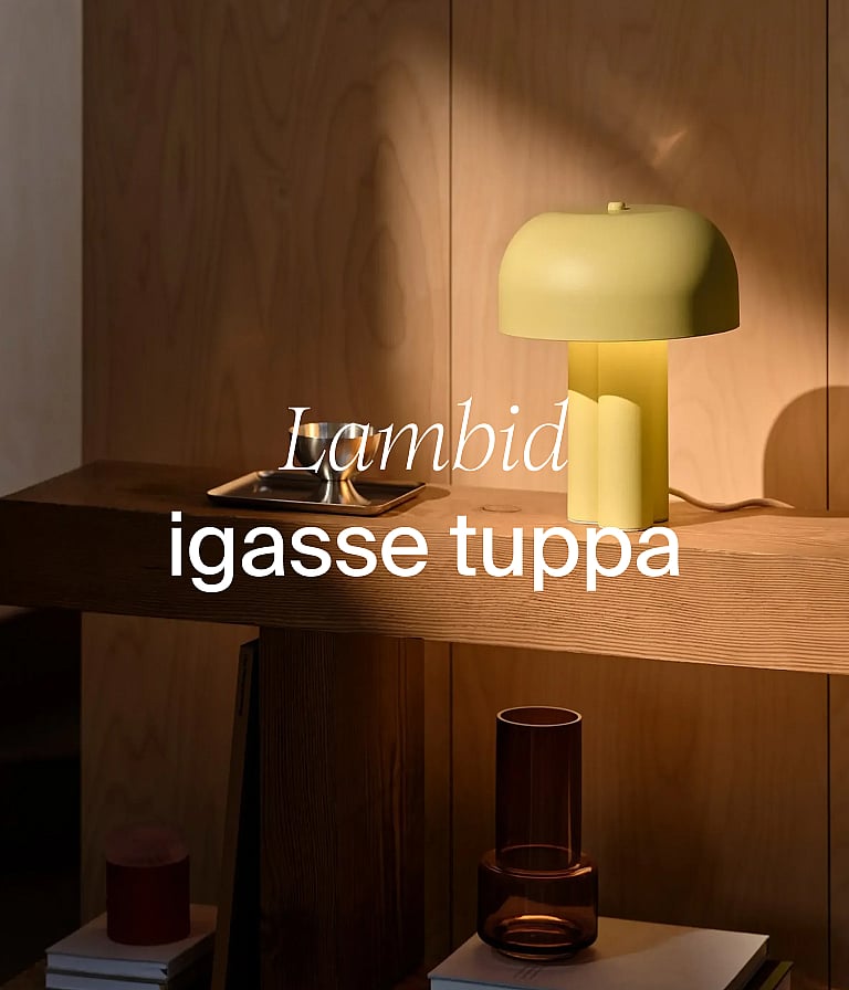 Hele-kollane seenekujuline lamp puidust konsoollaua peal puidust seina taustal. Tekst: „Lambid igasse tuppa.“