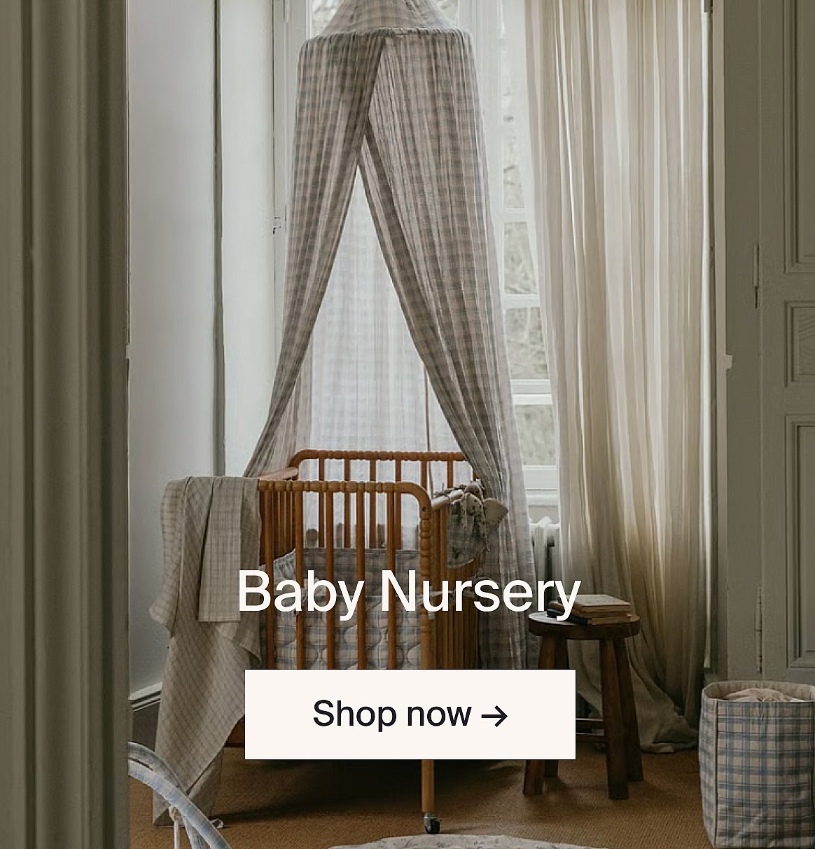 A cream fabric baby swing hangs in a bright room with a light wood table and chair.