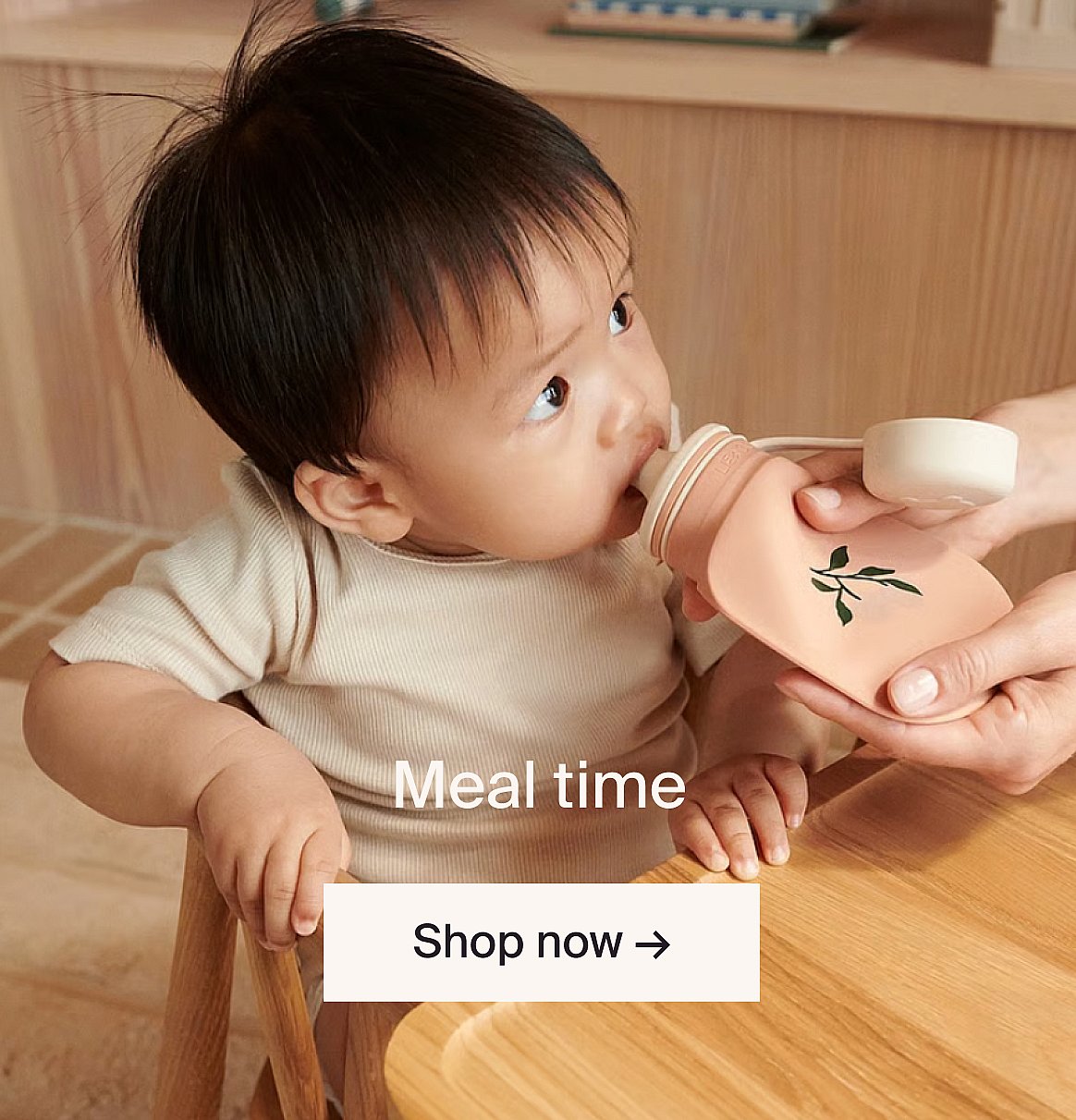 Baby meal on a wooden table: silicone bowls with fruit, yogurt, juice cup, spoon, and a wooden toy car.