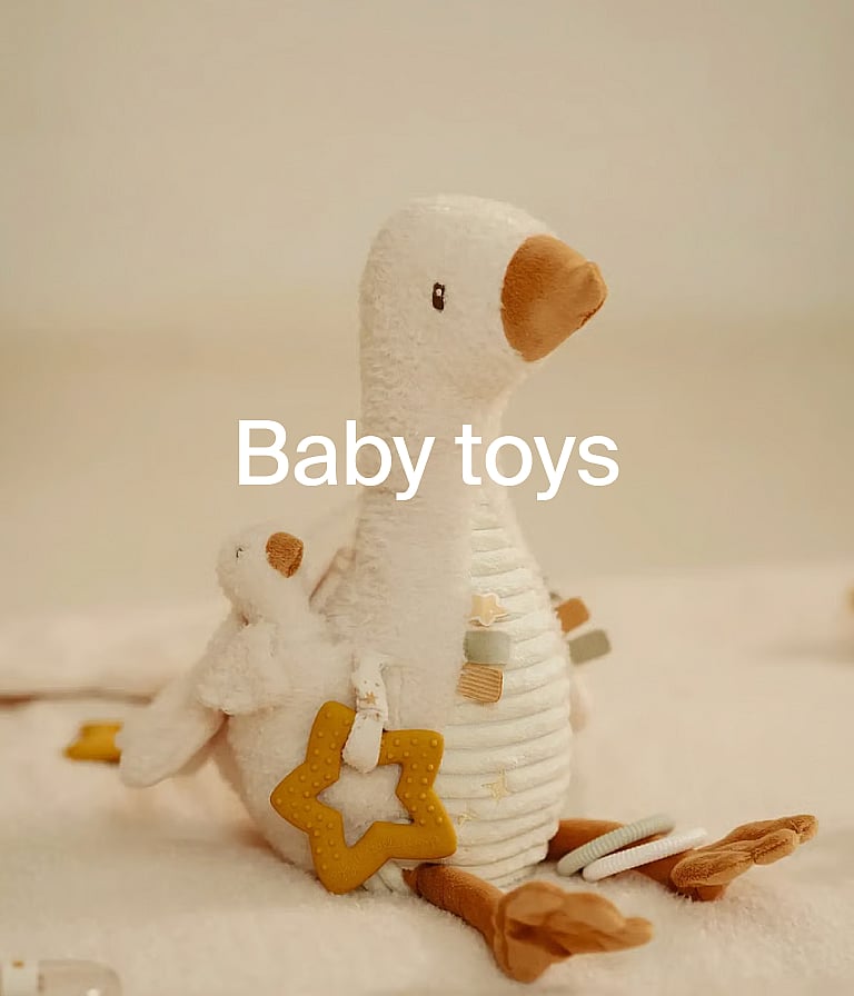 Two wooden pull-along toys, rattle, and plush toy on a dotted playmat. Rattan shelf and wooden floor behind.