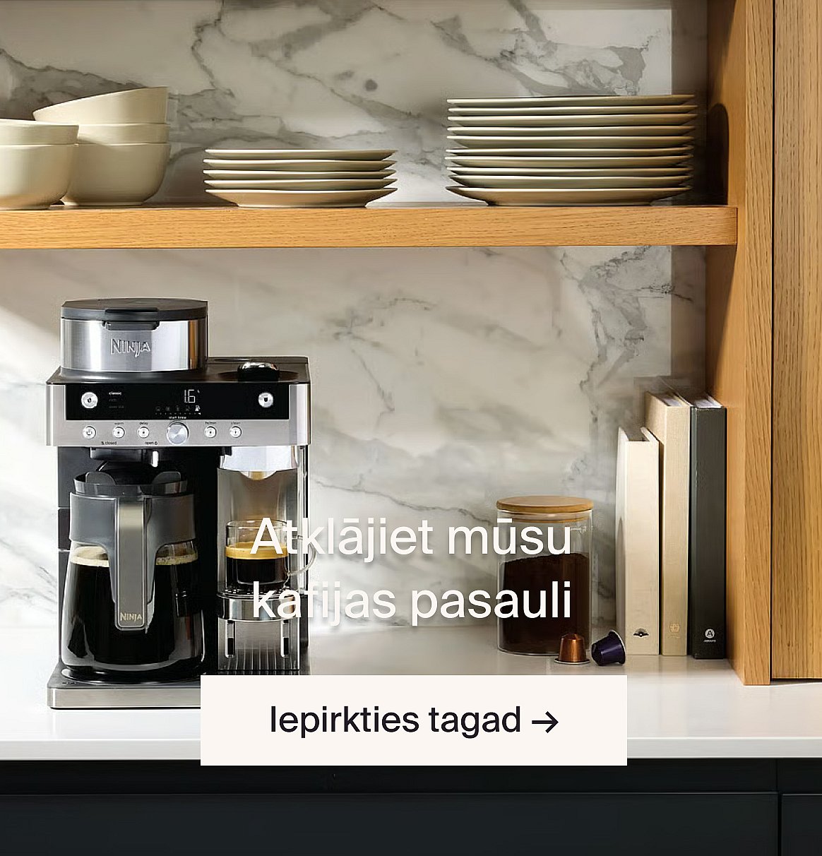 Ninja kafijas automāts, kas pagatavo kafiju uz virtuves galda. Marmora aizsargpanelis, koka plaukti ar bļodām un šķīvjiem.