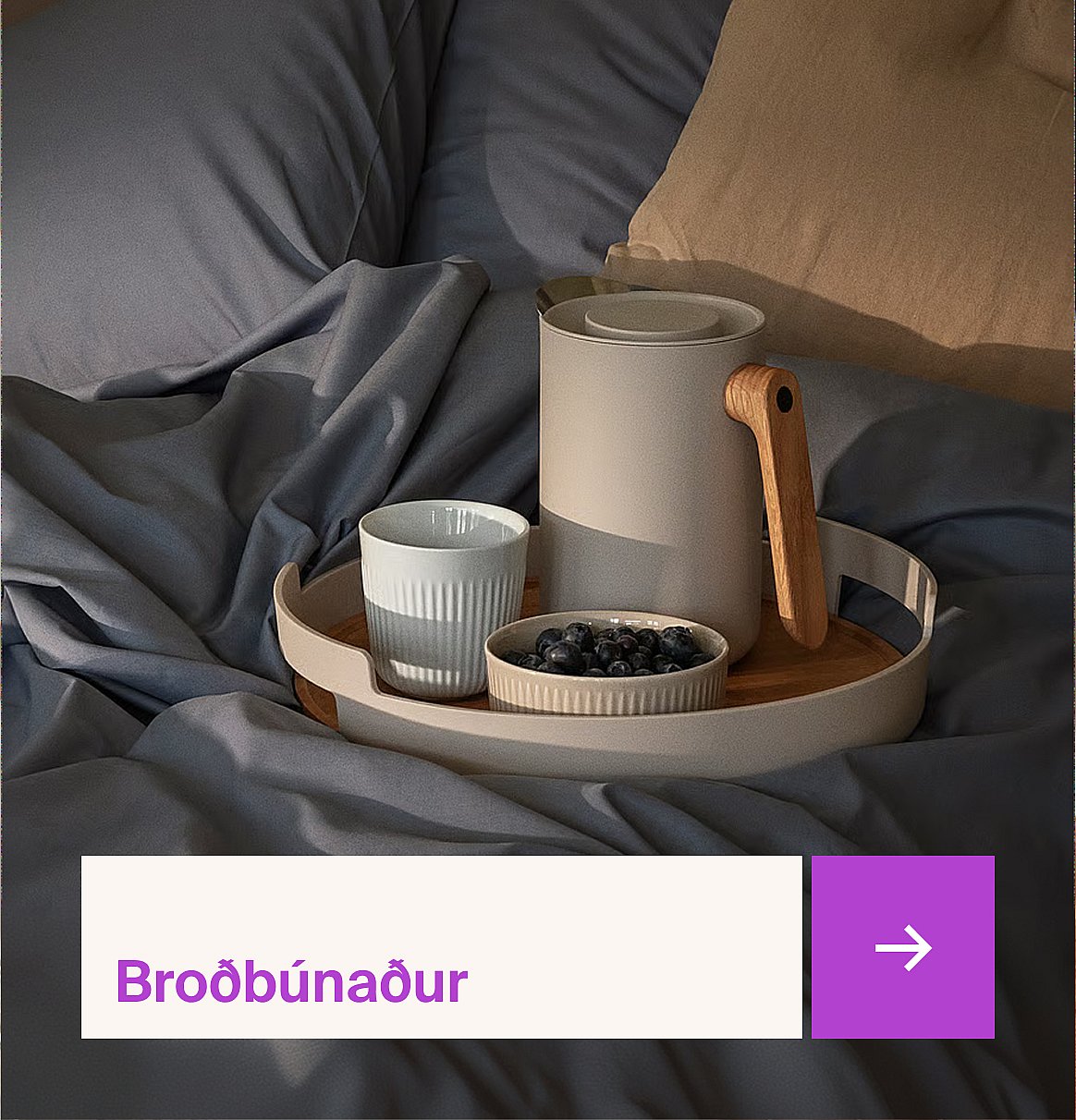 Morgunverðarbakki með bolla, könnu og bláberjum á rúmi með bláum lakum og beigem kodda.