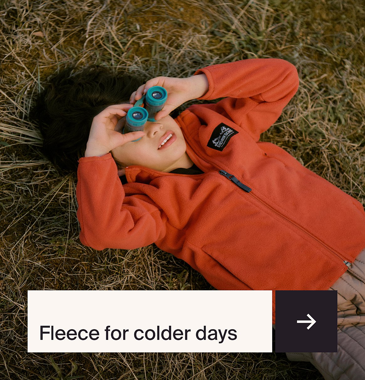 Child in blue Adidas tracksuit with white stripes, sitting on a blue chair, looking at viewer.