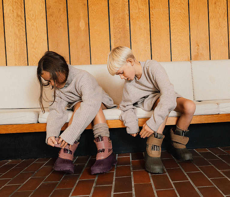 Skateboard leaning on a concrete bench, surrounded by six pairs of Puma suede sneakers in brown, orange, and black on