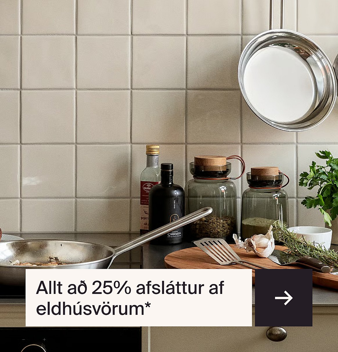 Eldhúsbekkur með steikingarpönnu, eldhúsolíum, kryddkrukkum, hvítlauk, jurtum og flísalögn á vegg bak við hann. Texti: "Allt að 25% tilboð á eldhúsvörum"