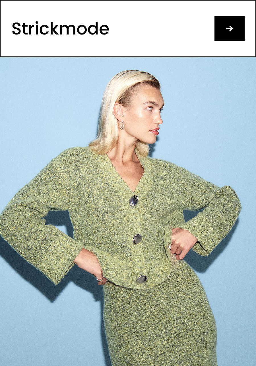 Blonde Frau in einer grünen Strickjacke und einem dazu passenden Rock, die Hände in die Hüften gestemmt, den Blick nach rechts gerichtet, vor hellblauem Hintergrund. Text: Strickmode