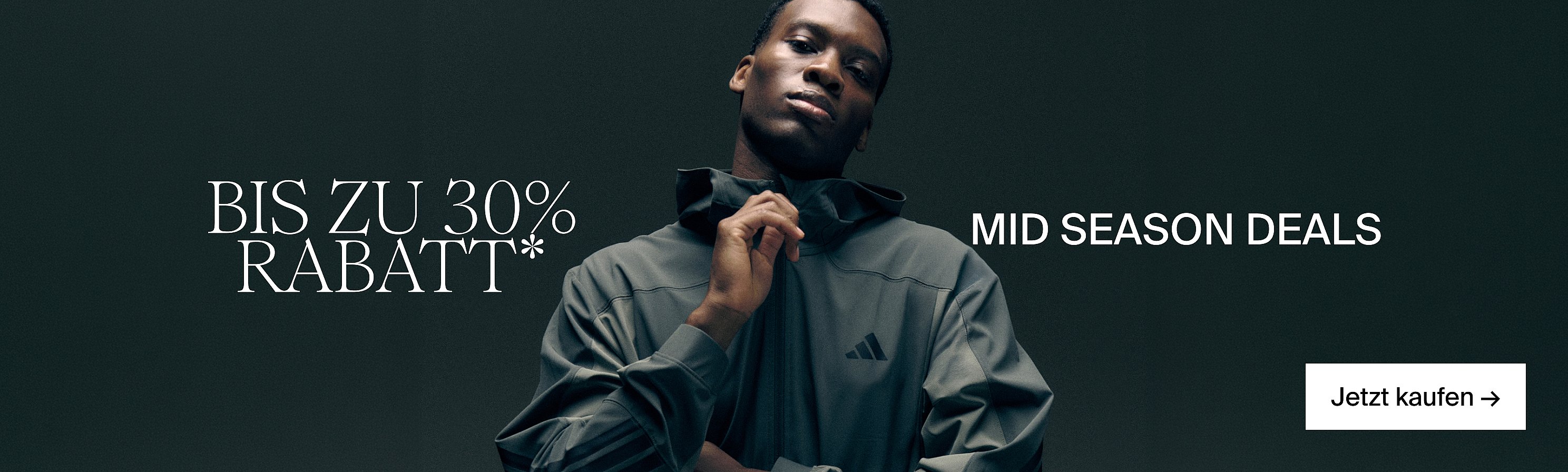 Mann in dunkler Kapuzenjacke vor dunklem Hintergrund. BIS ZU 30% RABATT*, MID SEASON DEALS, Jetzt einkaufen.