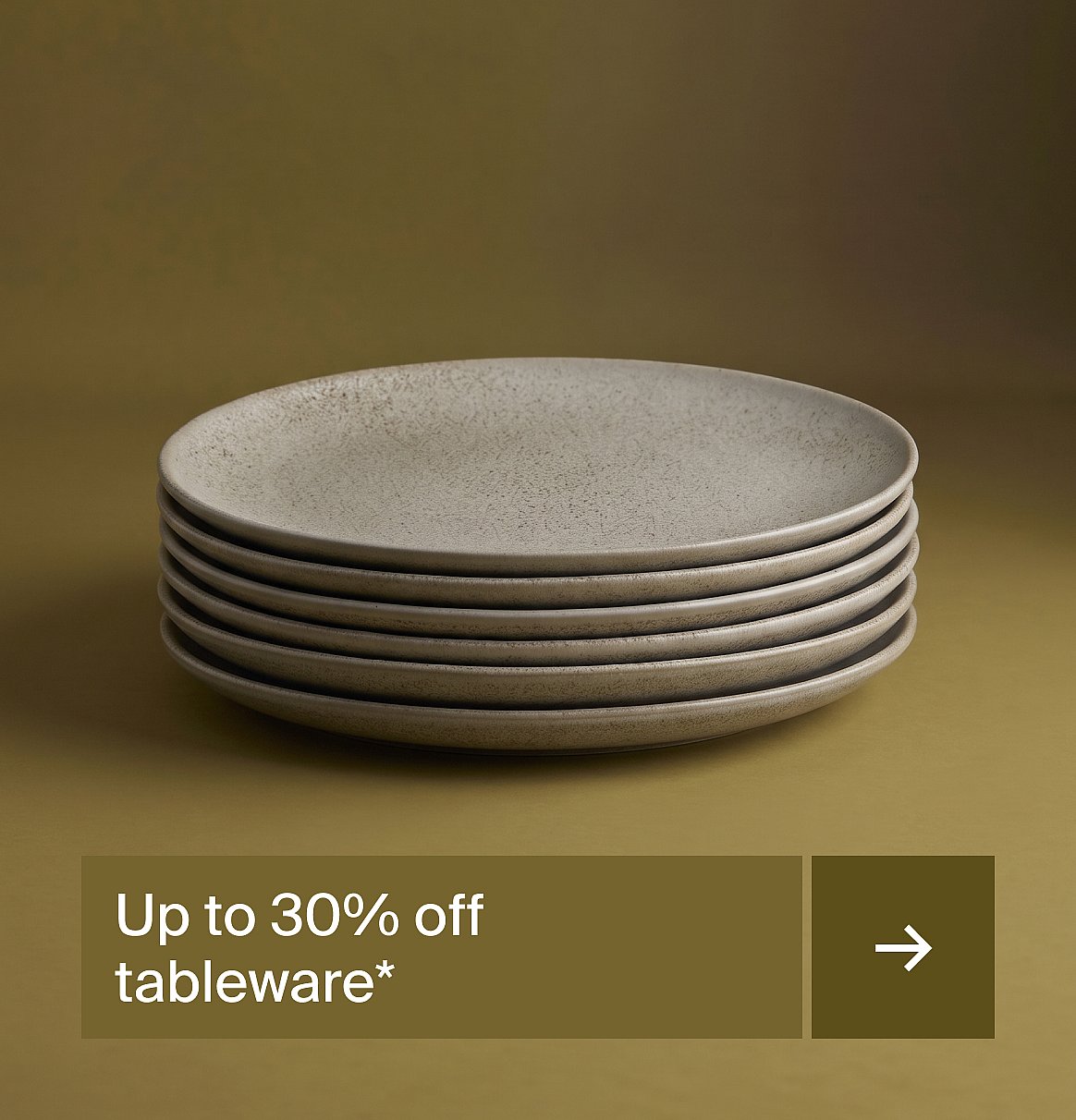 Stack of light gray speckled ceramic plates against a dark olive green background.
